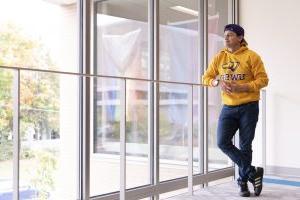 Student looking out the window of the Dreyfus University Center and wearing a gold UW-Stevens Point sweatshirt.